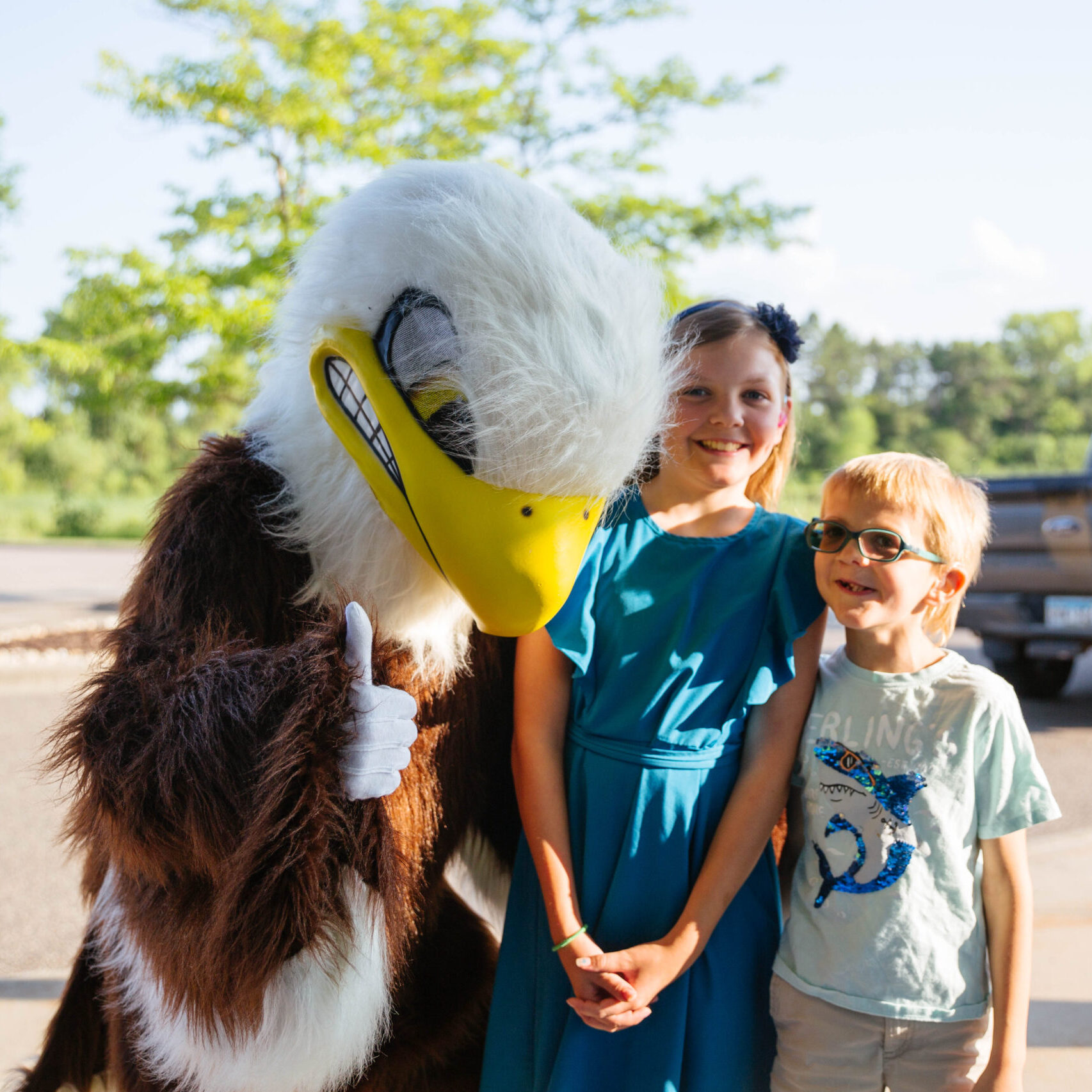 Soarin, New Life Academy's Eagle mascot, with two lower school students outside