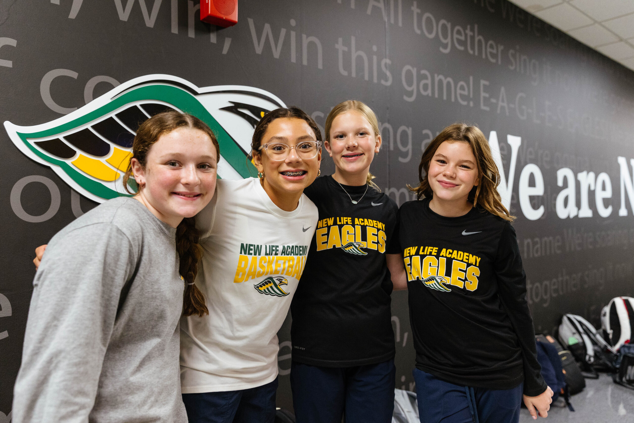 A group of middle school boys stands out by the New Life pond holding fishing poles and smiling at the camera.