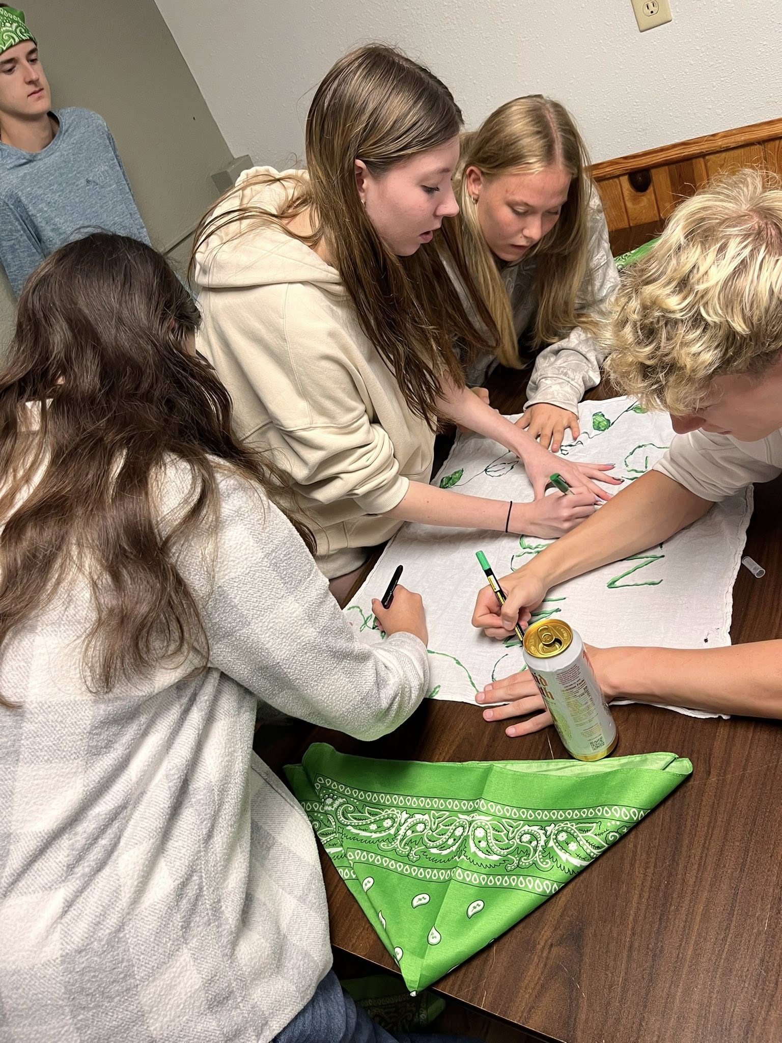 New Life Academy seniors at a table, drawing and decorating a team flag during the Senior Retreat.