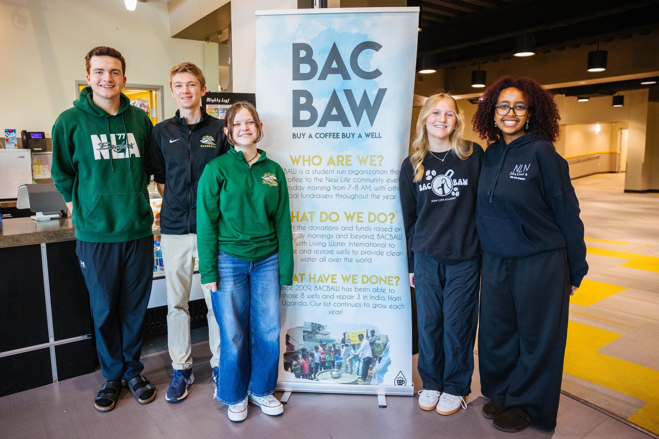 Group of middle school boys at New Life Academy work together on a science project using wood sticks and plastic to build a prototype
