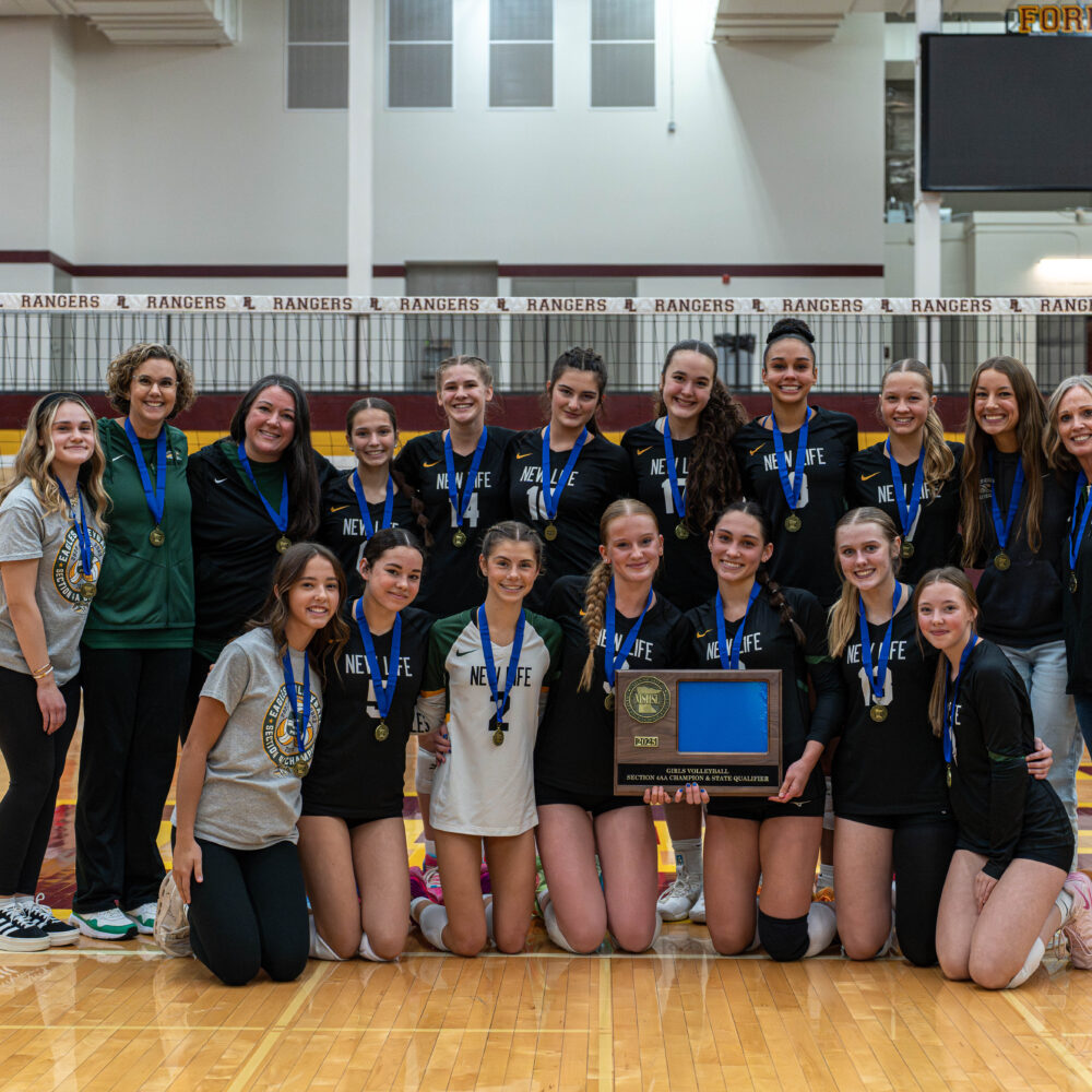 Four New Life Academy students smiling outdoors while holding Annual Fund signs and boxes during the 2025 campaign kickoff.